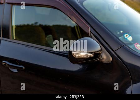 Specchietto laterale con un indicatore di direzione di un primo piano di un'auto Foto Stock