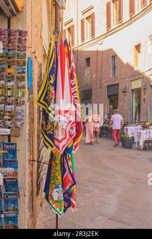 Siena, Italia, 2023 maggio 23: Vista ad angolo alto strada Siena piena di turisti e un negozio di vendita banner del Contrade (Palio). Toscana, Italia Foto Stock