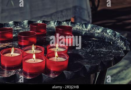 Candele votive rosse su candelabro di ferro Foto Stock