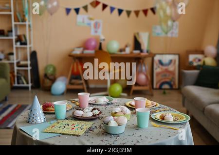 Immagine di sfondo della colorata camera per bambini decorata per la festa di compleanno con focus sul tavolo da pranzo con dolci e glitter, spazio copia Foto Stock