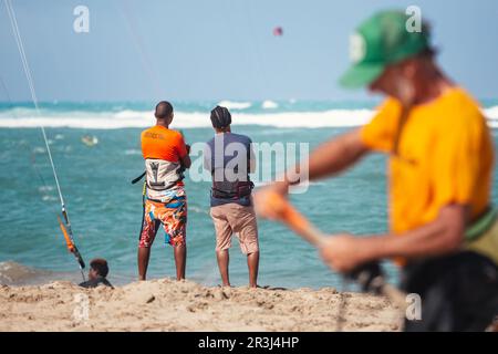 Persone attive sportive che godono di vacanze kitesurf e attività in una perfetta giornata di sole sulla spiaggia di sabbia tropicale Cabarete nella Repubblica Dominicana Foto Stock