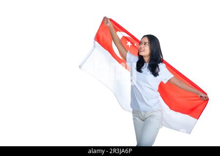 Le donne asiatiche celebrano la giornata dell'indipendenza di Singapore il 09 agosto tenendo la bandiera nazionale di Singapore isolata su sfondo bianco Foto Stock