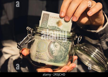 Banconota polacca zloty risparmio denaro in vaso di vetro. Donna irriconoscibile consumo moderato ed economia raccogliere denaro. Suggerimenti. B Foto Stock