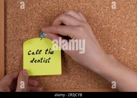 Donna pinning carta nota con frase chiamare il dentista a sughero bordo, primo piano Foto Stock