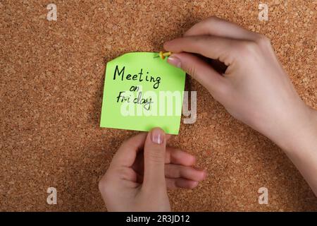 Donna pinning carta nota con frase riunione il Venerdì a sughero bordo, primo piano Foto Stock