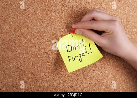 Donna pinning carta nota con frase non dimenticare di sughero bordo, primo piano Foto Stock