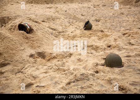 Tre caschi di fanteria americana M1 dalla seconda guerra mondiale sulla spiaggia. Foto Stock