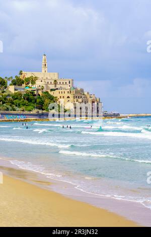 Tel-Aviv, Israele - 21 maggio 2023: Scena della spiaggia, con surfisti, altri, e la vecchia Jaffa. Tel-Aviv, Israele Foto Stock