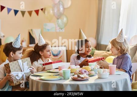 Diversi gruppi di regali di apertura per bambini felici alla festa di compleanno Foto Stock