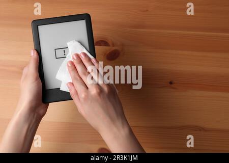 Donna che puliva lo smartphone con carta sul tavolo di legno, vista dall'alto Foto Stock