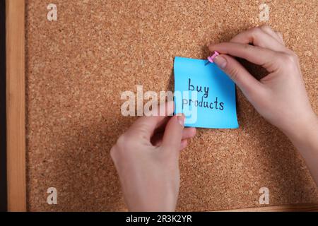 Donna pinning carta nota con frase Acquista prodotti per sughero bordo, primo piano Foto Stock