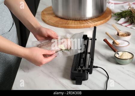 Donna che usa il sigillante per il confezionamento sottovuoto in cucina, closeup. Cucina sous vide Foto Stock