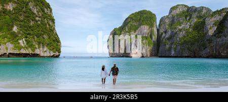 Coppia uomini e donne in luna di miele camminando su una spiaggia tropicale Foto Stock