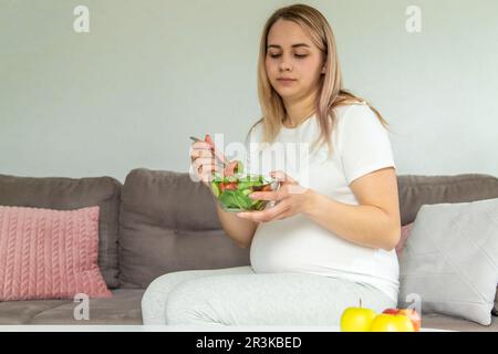 Una donna incinta mangia un'insalata con verdure. Messa a fuoco selettiva. Cibo. Foto Stock