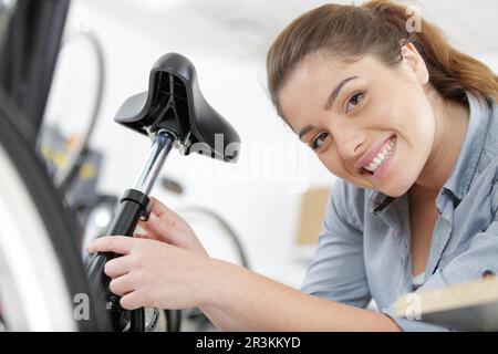 Felice repairwoman in piedi vicino a ciclo nel negozio di biciclette Foto Stock