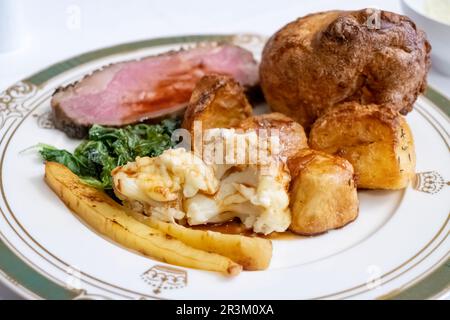 Una tradizionale cena Inglese completa a base di arrosto. Servito con striploin di manzo, patate arrosto, cavolfiore, pastinaca, cavolo, Yorkshire pudding e sugo di carne Foto Stock