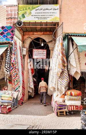 L'entrata al mercato principale di vendita di tappeti all'interno di Marrakech, Marocco souk Centrale. I tappeti pendono dalle bancarelle su entrambi i lati dell'ingresso Foto Stock