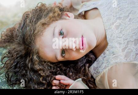 Ritratto di ragazza sdraiata sulla roccia guardando la macchina fotografica Foto Stock