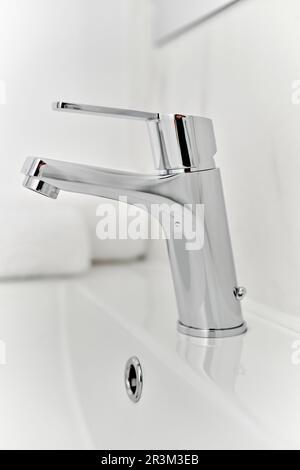 Elegante lavandino bianco e rubinetto metallico in bagno, primo piano Foto Stock