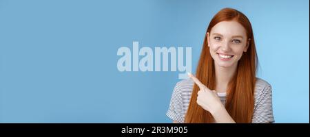 Primo piano attraente delicato tenero amichevole-guardare sorridente redhead donna mostra luogo che punta in alto a sinistra angolo indice dito grin Foto Stock