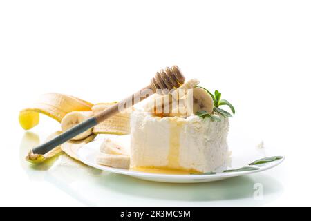 Porzione di cagliata di latte fatta in casa con fette di banana e miele, isolata su sfondo bianco. Foto Stock