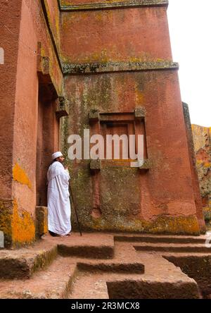 Sacerdote ortodosso etiope di fronte ad una chiesa scavata nella roccia, regione di Amhara, Lalibela, Etiopia Foto Stock