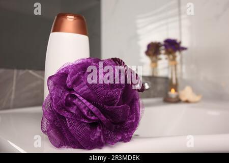 Soffio doccia viola e bottiglia di gel per il lavaggio del corpo sul lavandino in bagno, spazio per il testo Foto Stock