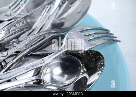 Lavaggio cucchiai, forchette e coltelli in argento con piastra, primo piano Foto Stock