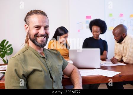 Ritratto di un uomo bianco sorridente con coda di cavallo, fantasioso brainstorming del team di codifica Foto Stock