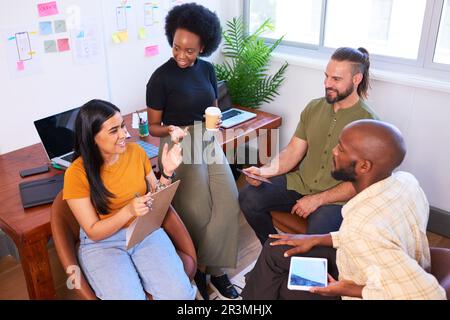 Vista dall'alto i membri del team che hanno una riunione informale, seduti in un ufficio creativo Foto Stock