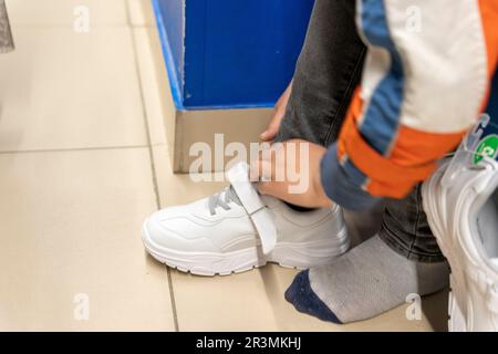 montaggio di nuove sneaker alla moda in un negozio di scarpe. Acquisto di nuove scarpe Foto Stock