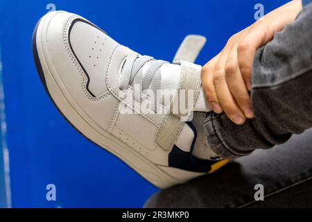 montaggio di nuove sneaker alla moda in un negozio di scarpe. Acquisto di nuove scarpe Foto Stock