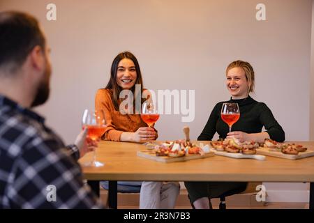 Un giovane gruppo di persone che si gustano un pasto a casa. Foto Stock
