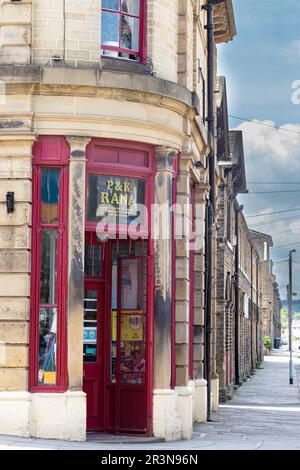 Un negozio d'angolo e una fila di case a schiera vittoriane in Caroline Street, Saltaire, West Yorkshire. Foto Stock