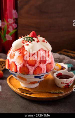 Dessert di ghiaccio coreano rasato con condimenti dolci, Bingsu di fragola su un tavolo di legno Foto Stock