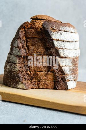 Vista frontale della pila di fette di pane di segale sul tagliere di legno sullo sfondo sfocato Foto Stock