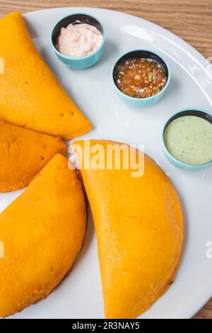 Vista dall'alto di appetitose empanadas colombianas con carne servita su piatto bianco con varie salse sul tavolo nel tradizionale ristorante latino-americano Foto Stock