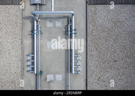 Dall'alto di costruzione di tubazioni e tubi metallici con pompe di circolazione e valvole con tubo verde vicino ai portelli delle fognature Foto Stock