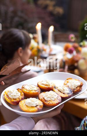 Gustose pesche tagliate alla griglia, servite con panna montata al formaggio, closeu Foto Stock