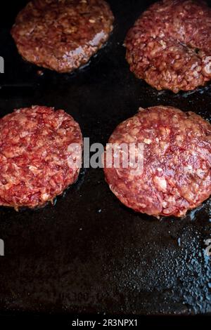 Hamburger che cucinano sulla griglia. Hamburger di manzo o maiale barbecue per hamburger. Hamburger su barbecue. Foto Stock