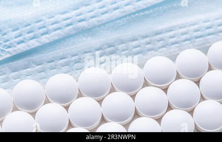 Righe di pillole e maschere mediche su sfondo bianco. Cura della salute, medicina, farmacia e concetto di malattia Foto Stock