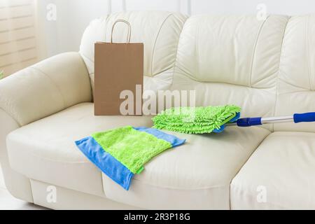 Spazzolone in plastica blu e verde con manico regolabile sdraiato sul divano - utensili per servizi di pulizia e pulizie domestiche Foto Stock