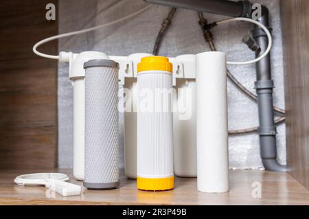 Installazione o sostituzione dei filtri di purificazione dell'acqua sotto il lavello della cucina Foto Stock