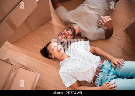 Vista dall'alto, coppia felice e trasferirsi in una nuova casa al piano terra e rilassarsi dalle scatole di imballaggio. Uomo, donna e fare una pausa in casa dalla proprietà Foto Stock