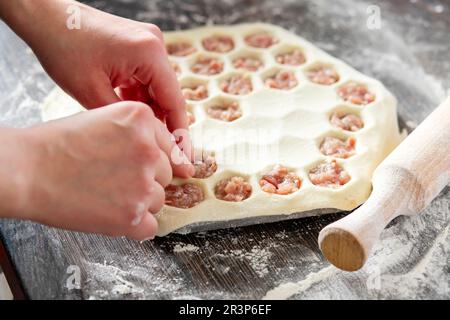 Il processo di fare gnocchi fatti in casa. Le mani delle donne scolpiscono gli gnocchi di carne Foto Stock