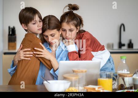 Bambini che abbracciano e sostengono la madre single stanca a casa Foto Stock