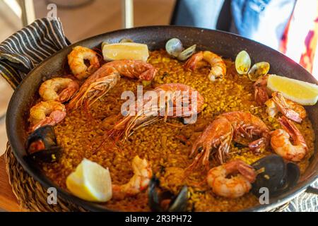 Tradizionale paella spagnola con gamberi, pinze, cozze, piselli verdi e limone fresco. Preparato in cuoco. Foto Stock