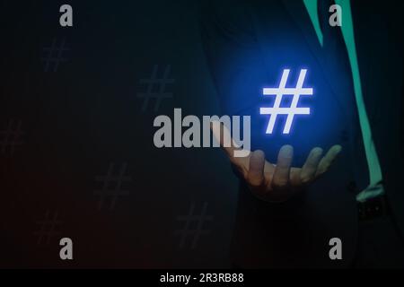 Concetto di hashtag. Uomo con segno su sfondo scuro, primo piano con spazio per il testo Foto Stock