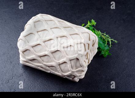 Bistecca di maiale grezza Kasseler come pezzo di pasta sfoglia, come primo piano offerto su una tavola nera con erbe aromatiche Foto Stock