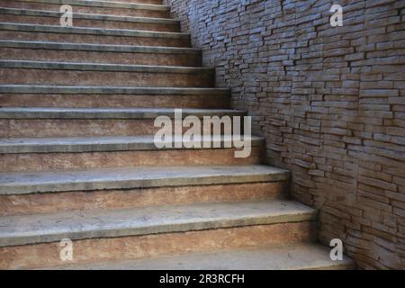 Vista delle belle scale vecchie vicino alle pareti in mattoni all'aperto Foto Stock